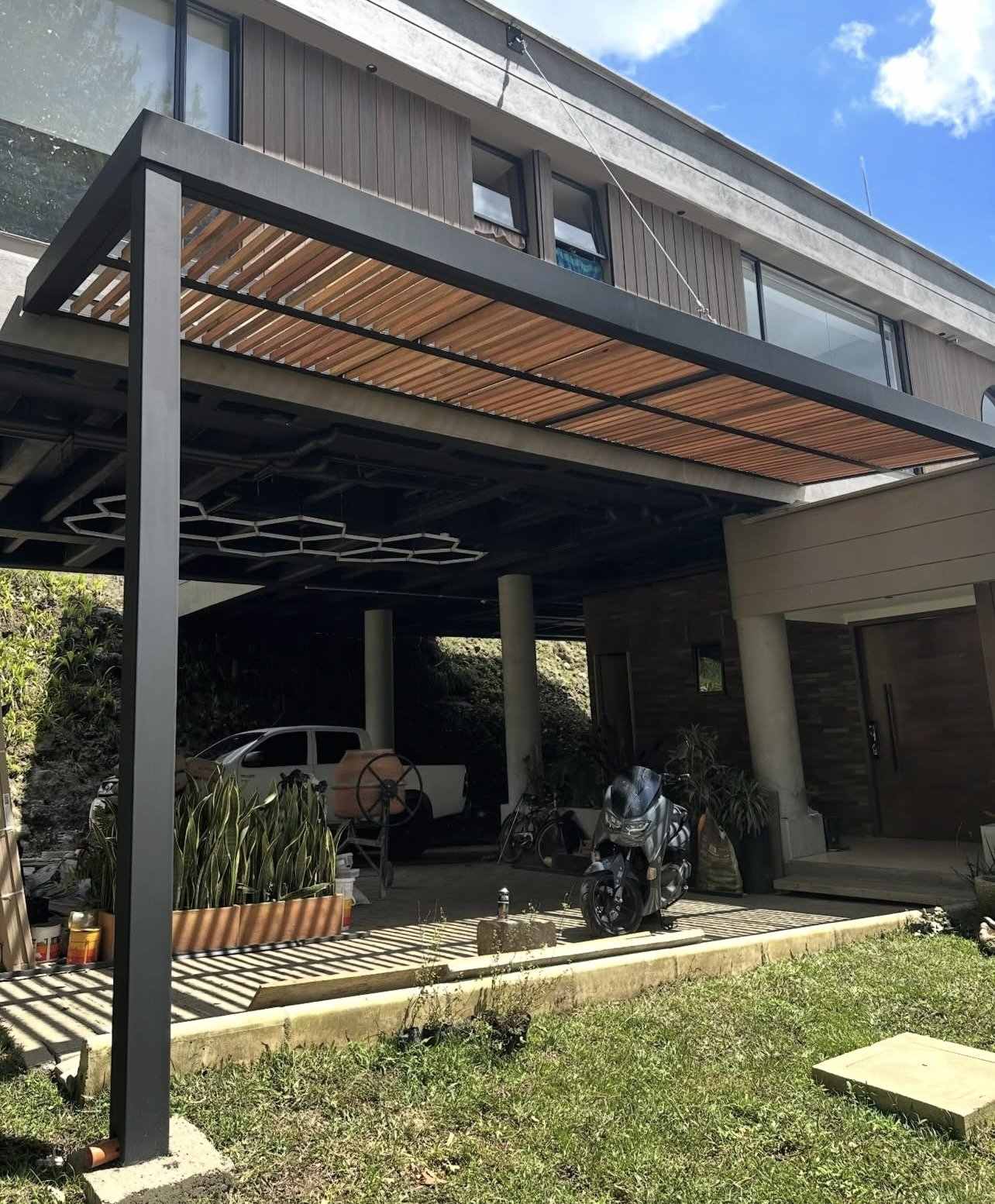 Pérgola en acero negro con listones de madera sobre un parqueadero
