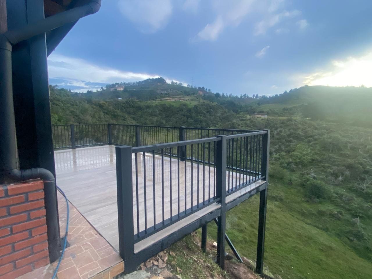 Terraza en metaldeck con baranda negra sobre una ladera, con montañas al fondo